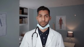 Male doctor standing in office wearing surgical mask