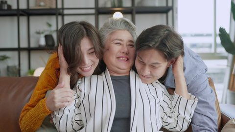 happiness asian family candid of daughter and son hug grandparent mother senior elder mom cozy relax on sofa couch surprise visiting in living room at home,together hug cheerful asian family at home