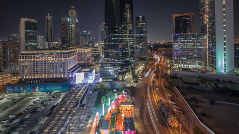 Dubai International Financial district with traffic on a road night timelapse. Panoramic aerial view of business office towers. Illuminated skyscrapers with hotels and shopping mall near downtown