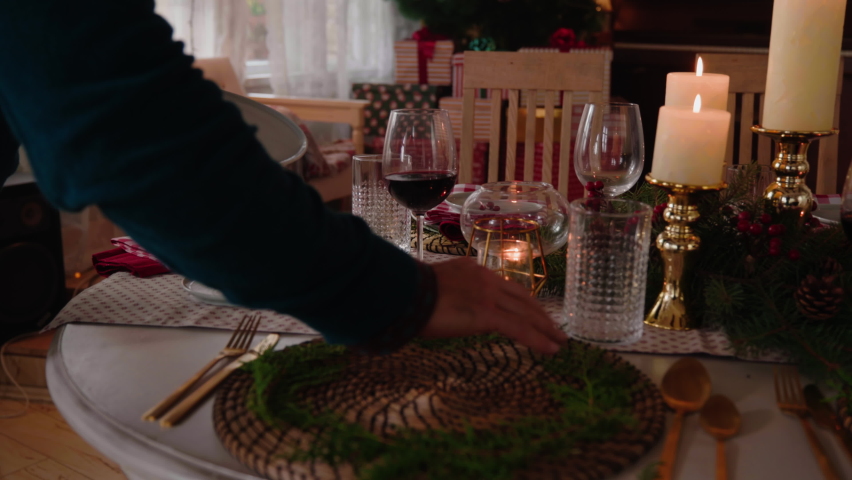Unrecognized man serving festive holiday table at home,putting napking on plate