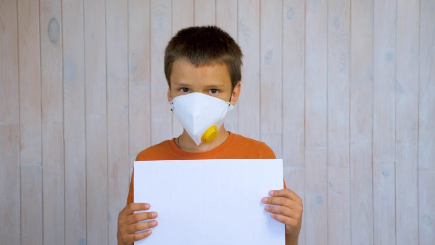 Wearing mask boy holding paper blank sheet for ads. little boy portrait camera. Respirator. Headshot boy portrait child looking at camera. Latin boy head shot kid portrait face mask child protection