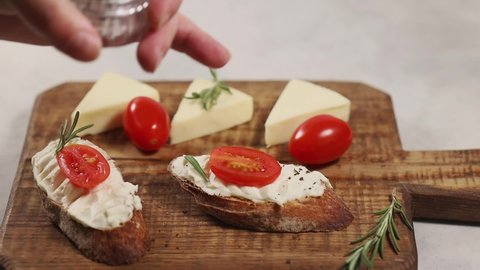 Sprinkling ground peppers on sandwiches with cream cheese and cherry tomatoes