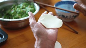 An old man in a Chinese family makes dumplings by hand
