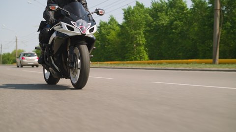 Couple enjoys contemporary motorcycle riding along highway against green trees at countryside on sunny summer day slow motion closeup