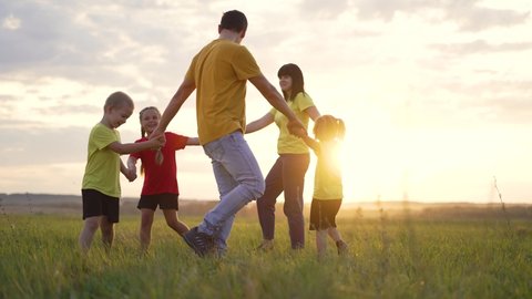 Happy family concept. Group of people hold hands in round dance. Children and parents are play in park on grass. Active lifestyle concept Family on green grass. Happy children play round dance in park