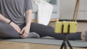 Young woman stretches her legs as shown on her video fitness training
