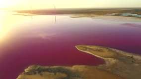 Shooting from a drone flying over a pink salt flat with a calm water surface. Bird's eye view. Syvash Lake, Ukraine, Europe. Cinematic aerial shot. Discover the beauty of earth. Filmed in 4k video.