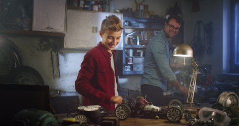 Cinematic shot of curious teenage boy  is working on modification of power of his remote control toy car for engineering project at school in his father workshop.