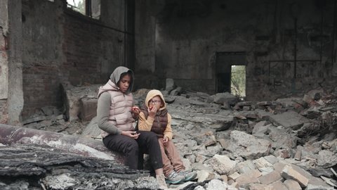 Stab shot of two little African-American homeless girls sitting on ruins of their demolished house
