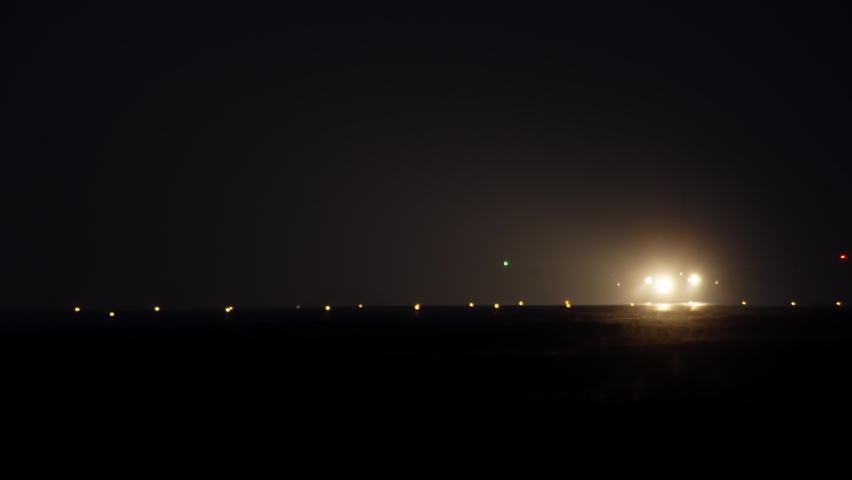 Night airport with light on the runway on which the plane travels and takes off. Foggy weather and the light of an airplane taking off into the sky. Royalty-Free Stock Footage #1082410177