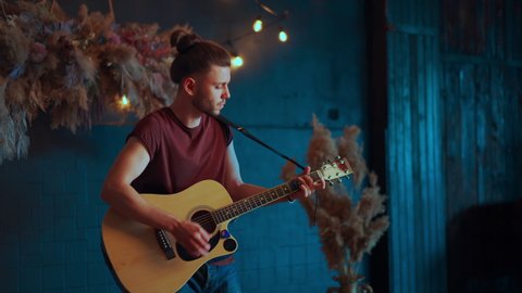 Male musician playing acoustic guitar. Guitarist plays classical guitar on stage in concert Handsome young hipster male guitar player perform private party 