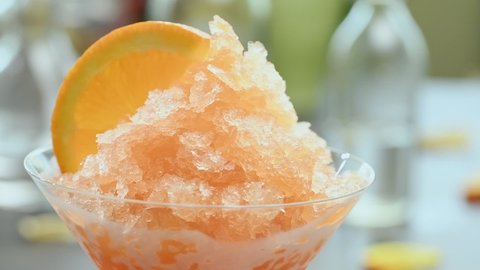 Scooping an aperol spritz granita with a spoon.