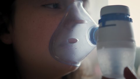 Close up footage of childhood asthma inhaling mask illnesses little girl doing aerosol independently .
