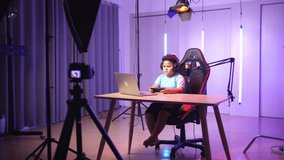 Asian Little Boy Holding Mobile Phone And Read Comment In Laptop Computer Then Talking To Camera While Live Stream, Professional Light Equipment 
