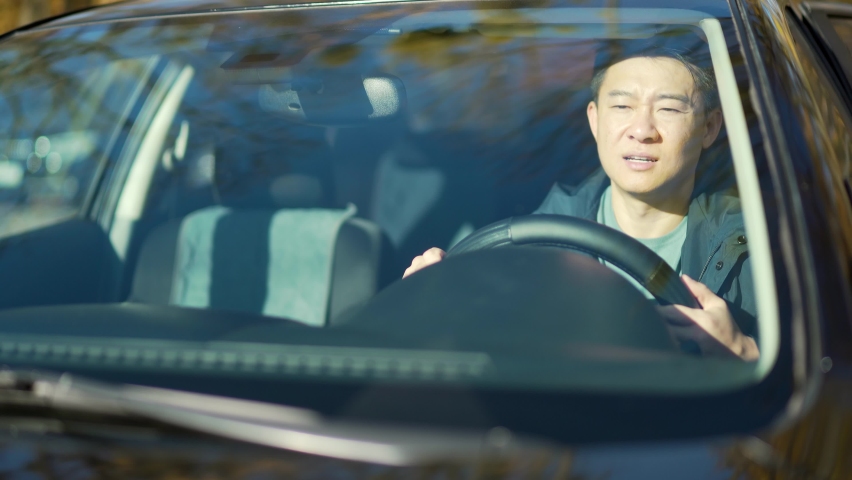 Furious angry asian man standing in a traffic jam beeps and hurries. Sitting in the car. Irritated young business male tired driver in automobile. Stressful commuting to be late work Royalty-Free Stock Footage #1082415601