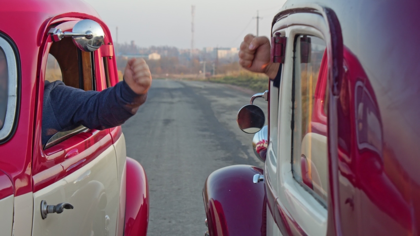 two drivers play rock paper scissors between cars before a race or competition. A competition between men.