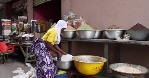 NIMA, GHANA - 30 OCT 2021: Muslim women seed grain food market Accra Ghana. Urban market stall along busy poor neighborhood street. Day to day living poor economy.