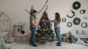 Young Caucasian Family of Four Decorating Christmas Tree Together at Home. Christmas, New Year and Winter Holiday Celebration Concept - Powered by Shutterstock - Get 15% off with code: PIKWIZARD15