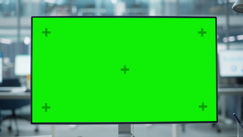 Desktop Computer Monitor with Mock Up Green Screen Chroma Key Display Standing on the Desk in the Modern Business Office. In the Background Glass Wall with Big City Office. Zoom Out Shot. Royalty-Free Stock Footage #1082416558
