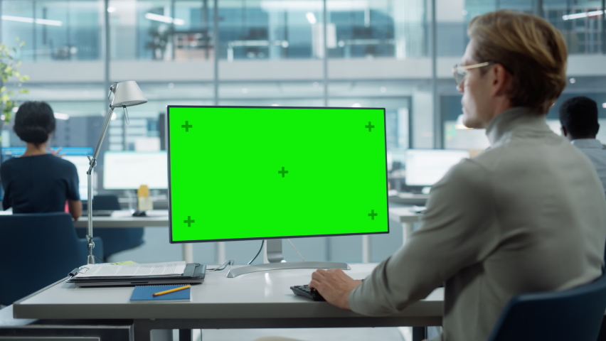 Close Up Over the Shoulder Shot of a Businessman Working on Desktop Computer with Chroma Key Green Screen Mock Up Display. Digital Projects Manager Typing Data, Using Keyboard and Mouse. Royalty-Free Stock Footage #1082416564