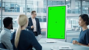 Company Operations Manager Holds Meeting Presentation for a Team of Economists. Adult Male Uses Digital Whiteboard with Vertical Green Screen Mock Up Display. People Work in Business Office. - Powered by Shutterstock - Get 15% off with code: PIKWIZARD15