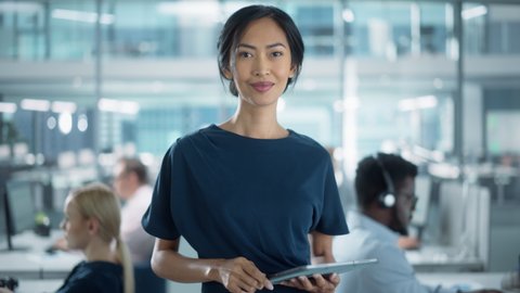 Successful Businesswoman in Stylish Dress Using Tablet Computer, Standing in Modern Diverse Office Working on Financial, Business and Marketing Projects. Portrait of Beautiful Asian Manager.