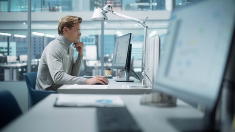 In Big Diverse Corporate Office: Portrait of Handsome Manager Using Desktop Computer, Businessman Managing Company Operations, Analysing Statistics, Commerce Data, Marketing Plans.