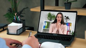 Man doctor psychologist at office listen examines patient client online video call webcam laptop, writes symptoms in notebook. Depressive woman in computer screen emotionally talks about his problem