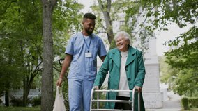 Senior woman and caregiver outdoors on a walk with walker in park, talking. - Powered by Shutterstock - Get 15% off with code: PIKWIZARD15