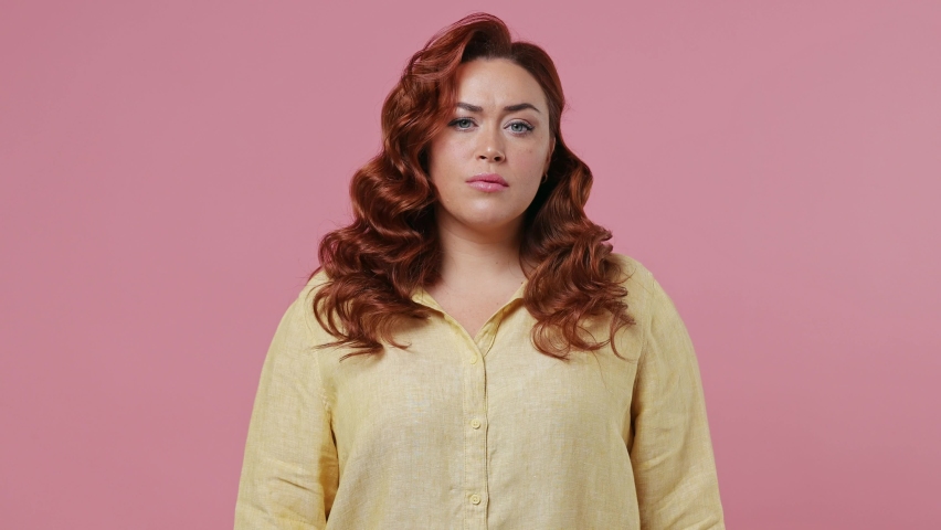 Scared shocked young ginger chubby overweight woman 30s years old wears yellow shirt look camera covering hiding face with hands peep through fingers isolated on plain pink background studio portrait Royalty-Free Stock Footage #1082429908