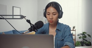 Happy asia girl record a podcast on laptop computer with headphones and microphone talk with audience at living room. Female podcaster make audio podcast from her home studio. Stay at house concept.