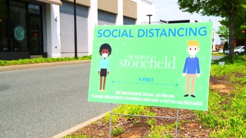 Charlottesville, USA - April 29, 2021: Sign for social distancing keep six feet apart at the shops at Stonefield strip mall center and wear face cover