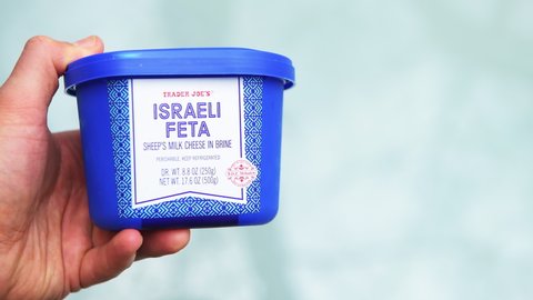Nellysford, USA - April 29, 2021: Macro closeup of hand holding product of Israeli sheep milk feta cheese dairy in brine with sign label storebought at Trader Joe's