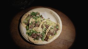 This video shows a diner's hands taking a carne asada street taco from a plate.