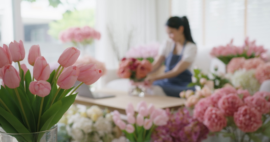 Defocus background of Asia people SME woman tied bow sell flower gift product wrap parcel send by same day sale order fulfilment dropshipping postal solution. Happy at home workspace in digital store.