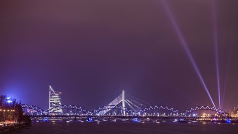night timelapse in Riga, Latvia. lit bridge and fireworks light up the sky over Daugava river