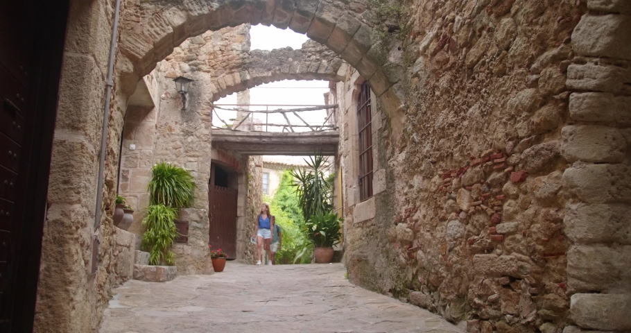 Couple Wandering In The Medieval Street Of Pals, Catalonia, Spain - wide, static shot