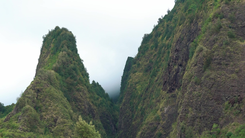 Wide shot of rural green mountains at Iao Valley with dense fog in background - Hawaii,Island