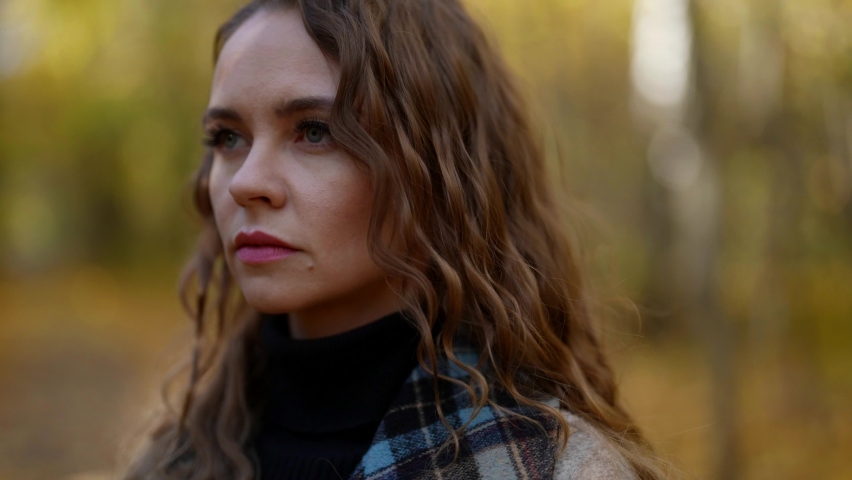 portrait of sad young woman in forest in autumn day, walking alone