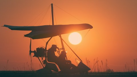 The preparing for testing flight by hang glider on beautiful sunset background