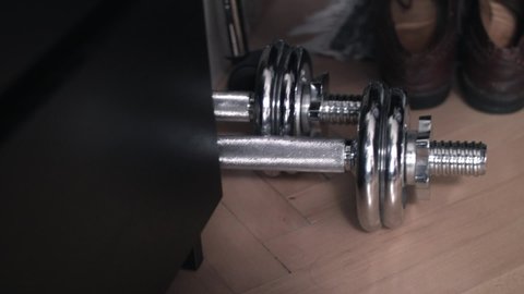 Pan to left shot of dumbbells and shoes on the floor, close up