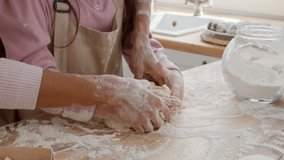 Unrecognizable Mom And Little Daughter Kneading Dough Together Baking Pastry In Modern Kitchen At Home, Wearing Aprons, Closeup Of Hands. Slow Motion, Cropped