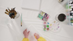 Time lapse. Flat lay. Little girl painting with acrylic paint on canvas with her mother for a distant learning art project.