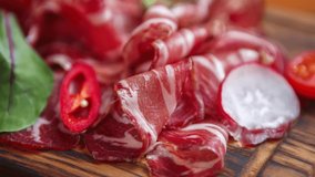 Stock food video of sliced Spanish jamon meat for wine appetizer. Gourmet Italian prosciutto ham served on rustic wooden plate for dinner