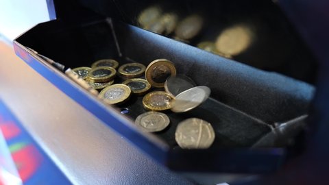 SWANAGE, UK - NOVEMBER 5, 2021: British coins falling from a change machine inside a gaming arcade in Swanage, Dorset, UK.