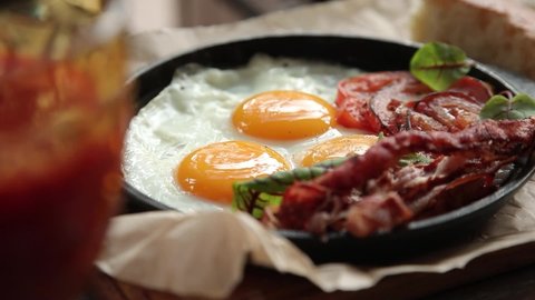Traditional full English breakfast close-up. girl cuts fried eggs and dips bread in yolk