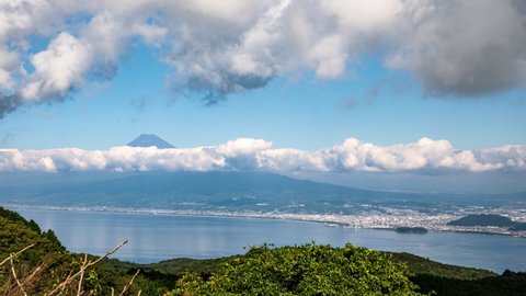 Clouds boiling above Mt. Fuji that seems to float in the fresh green and the sea 