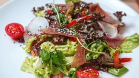 Stock food video of Gourmet salad with jamon meat and fresh vegetables. Delicious Italian prosciutto ham, reddish and lettuce served for lunch in restaurant