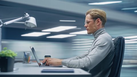 360 Degree Modern Office: Handsome Businessman Sitting at His Desk Working on a Laptop Computer. Man working with Big Data e-Commerce Analysis. Energetic Fast Tracking Shot. Camera Moving Around