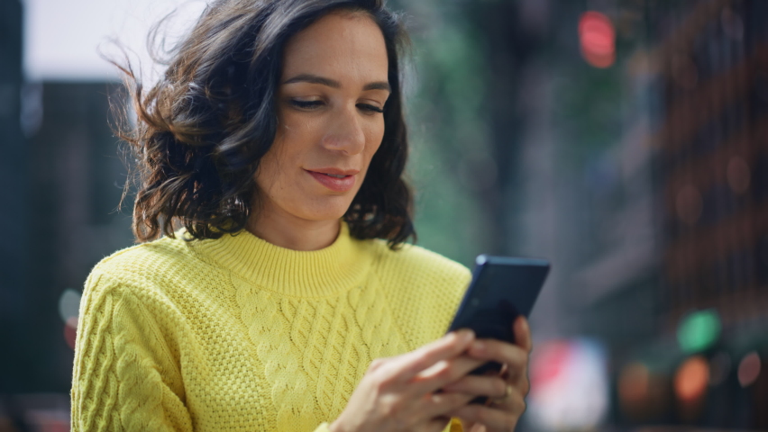 Portrait of Beautiful Happy Latin Woman Standing, Using Smartphone on a City Street. Smiling Gorgeous Hispanic Female with Lush Dark Hair using Mobile Phone for e-commerce, Online Shopping Royalty-Free Stock Footage #1082482096